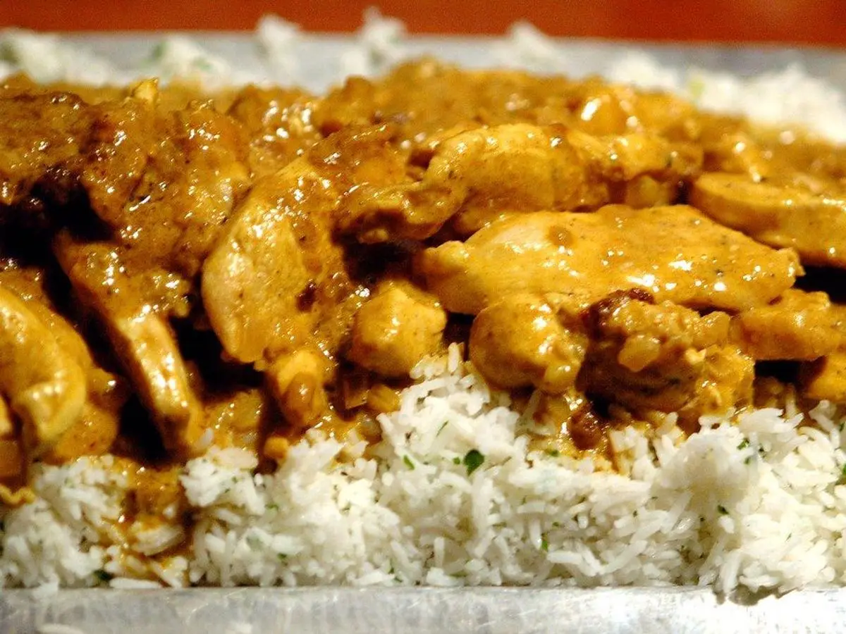 Pollo troceado al curry sobre un lecho de arroz blanco