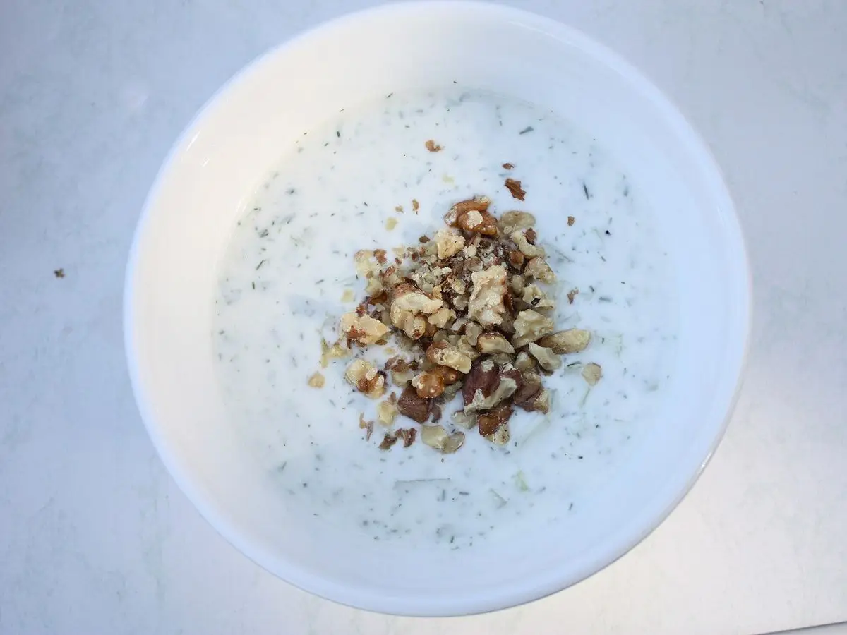 Cuenco blanco de tarator, sopa fría de yogur con pepino y eneldo, con nueces picadas en el centro