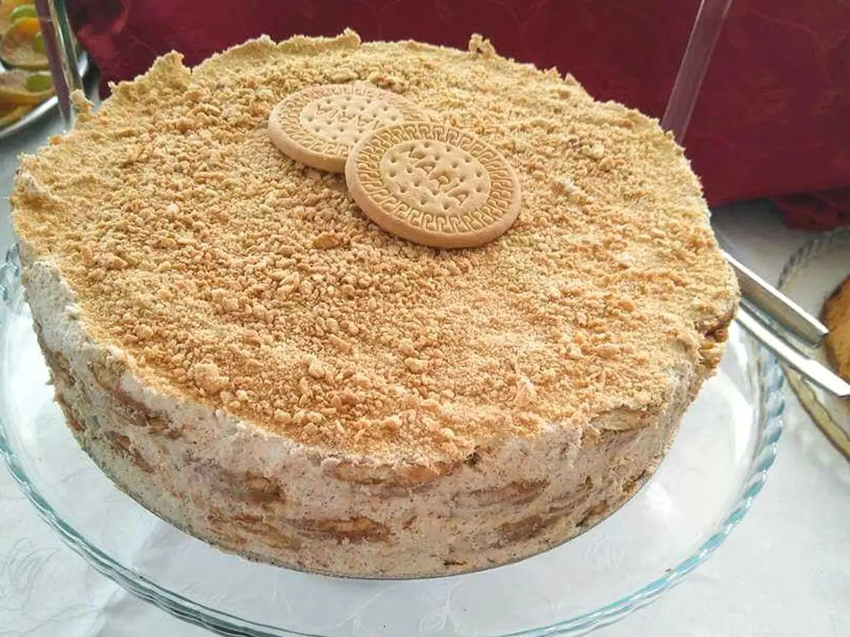 Tarta de galletas con capas de crema, cubierta de galleta triturada y dos galletas María encima