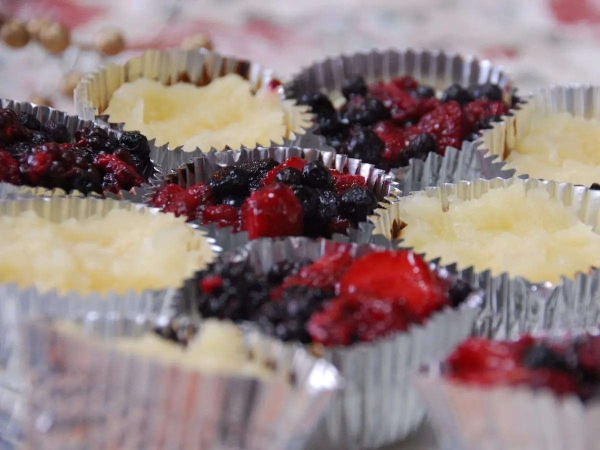 Minitartas de queso en cápsulas de papel plateado, con frutos rojos y base de galleta