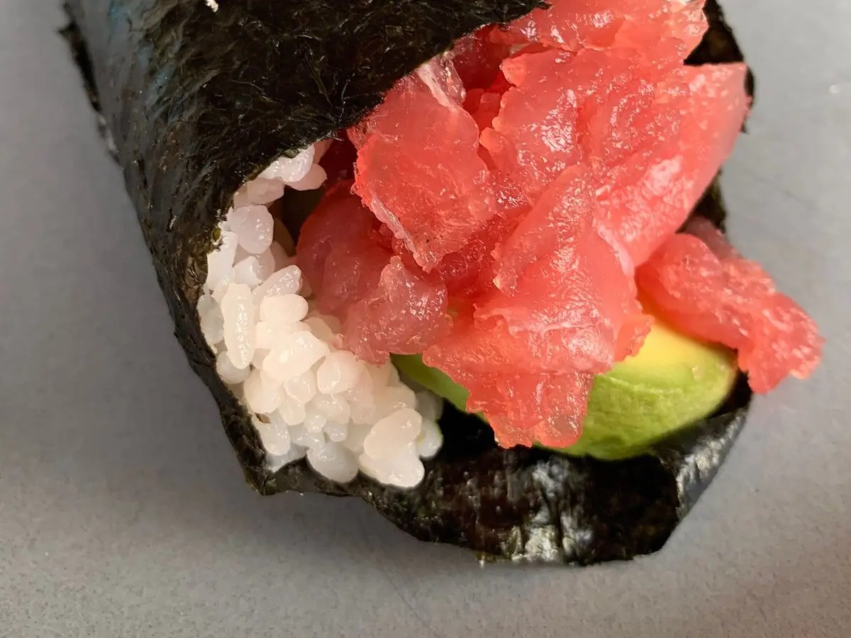 Temaki, cono de alga nori relleno de arroz, pescado rojo en dados y aguacate