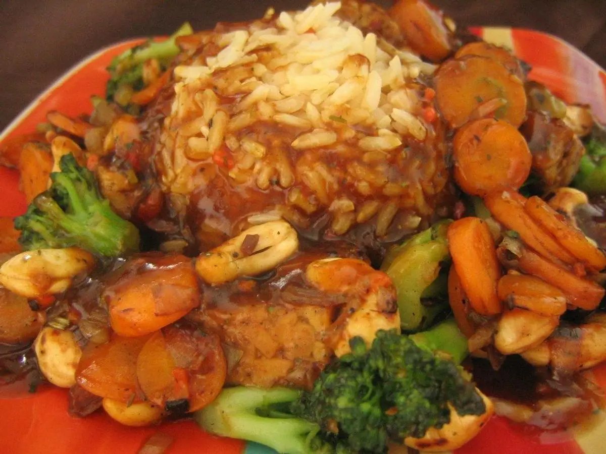 Plato con arroz, tempeh con anacardos, zanahoria y brócoli en salsa brillante