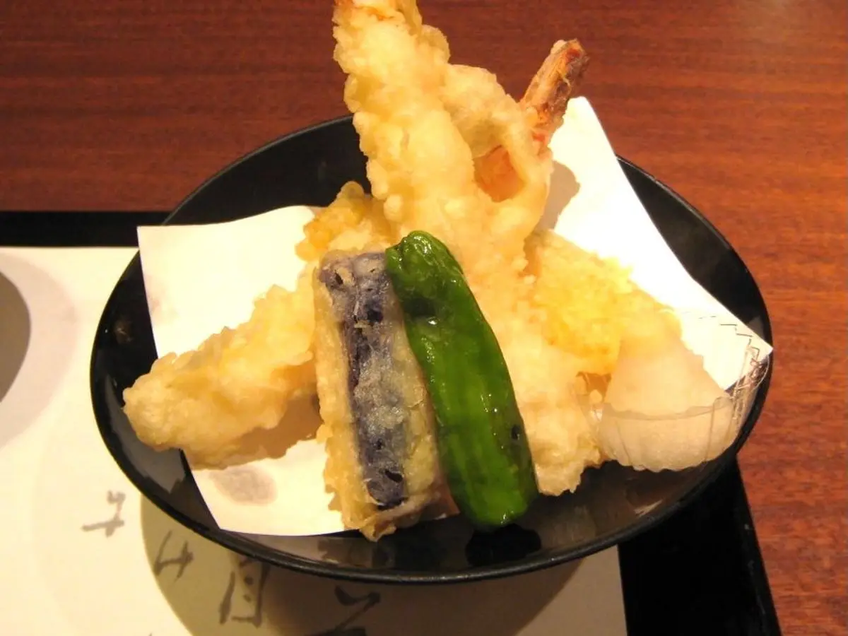 Tempura de gambas y verduras variadas, con berenjena y pimiento verde, en un cuenco negro