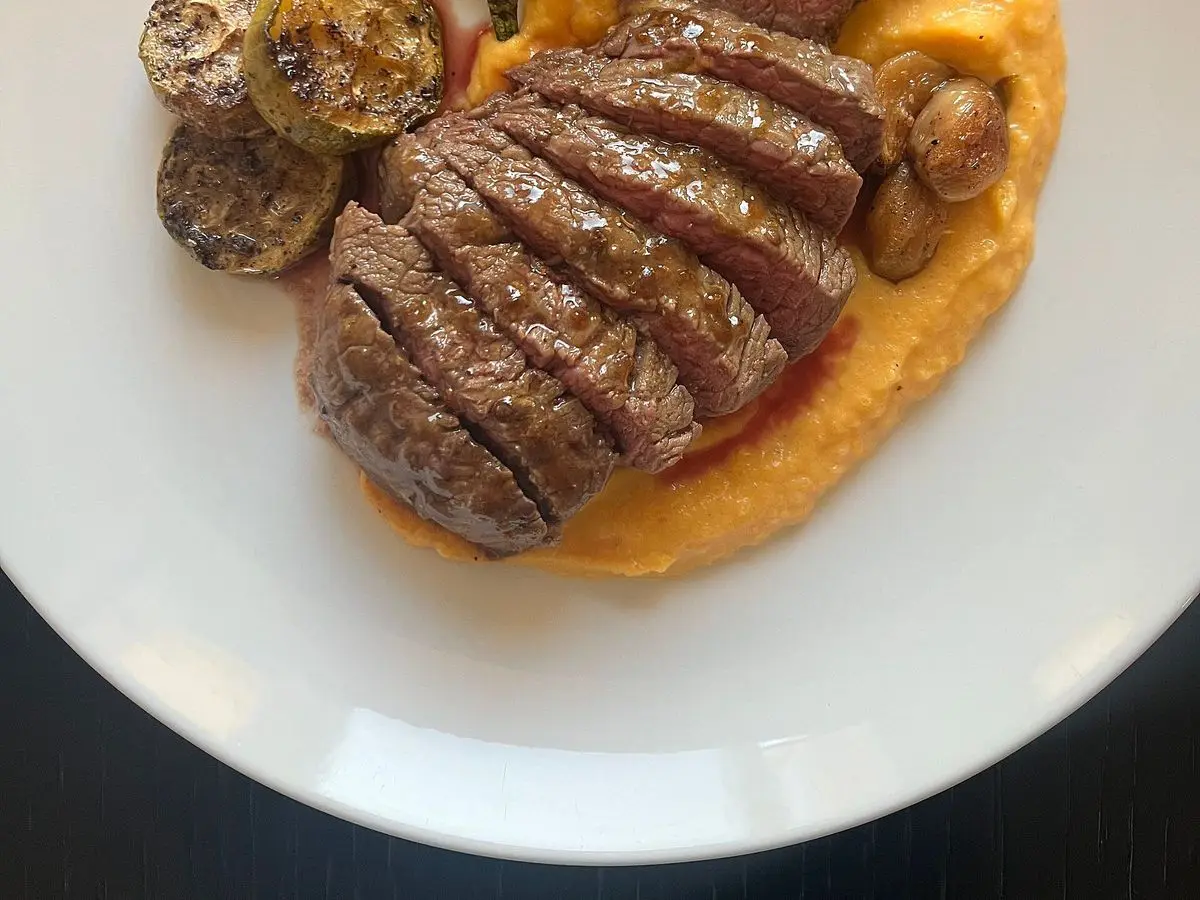 Plato con filetes de ternera en lonchas sobre crema de calabaza, con verduras salteadas y champiñones