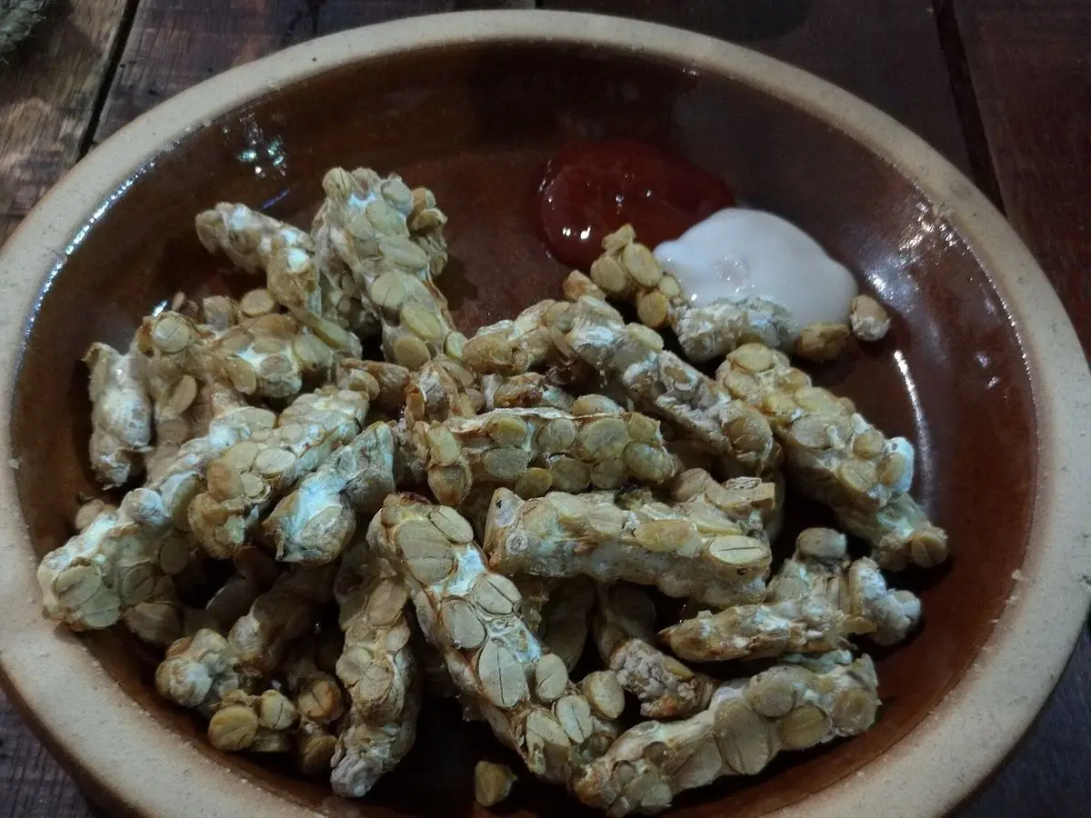 Cuenco de barro con tempeh frito en trozos con guindilla sobre un fondo claro