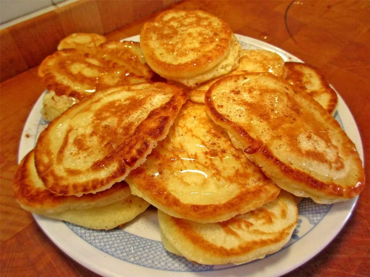 Plato con torre de tortitas griegas doradas bañadas en miel