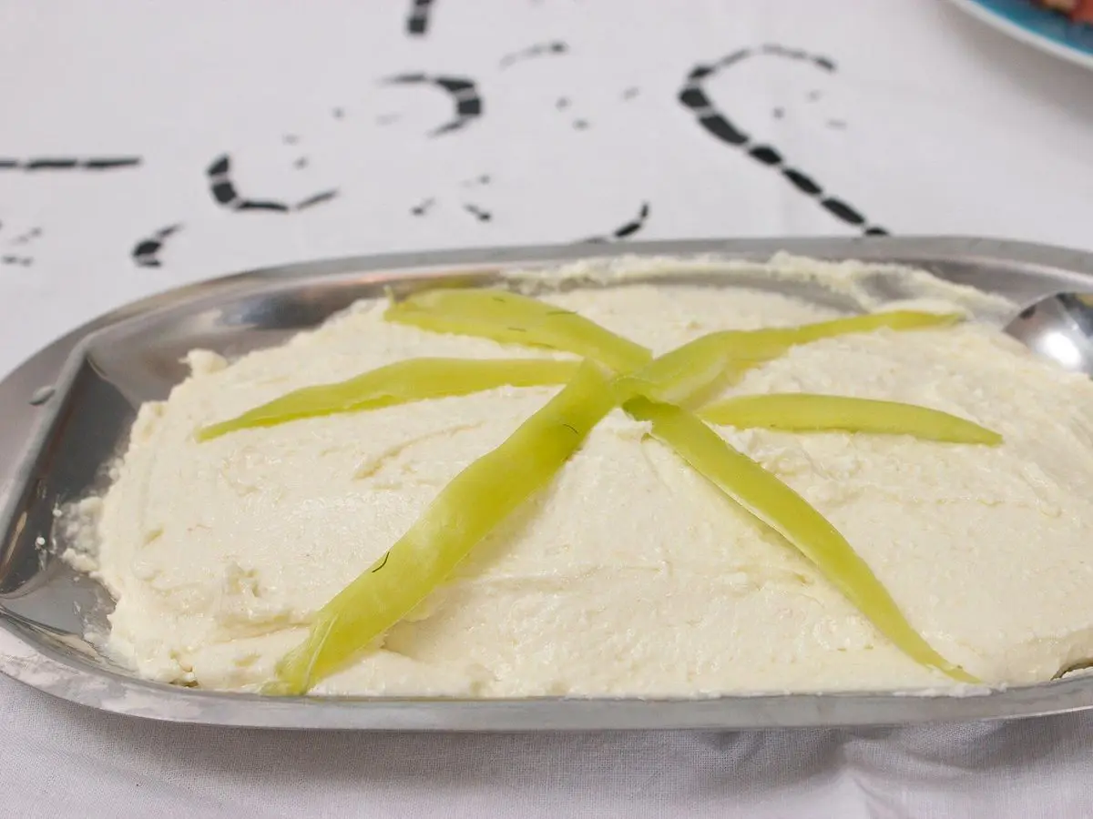 Bandeja metálica con crema de queso feta tirokafteri decorada con tiras de pimiento verde