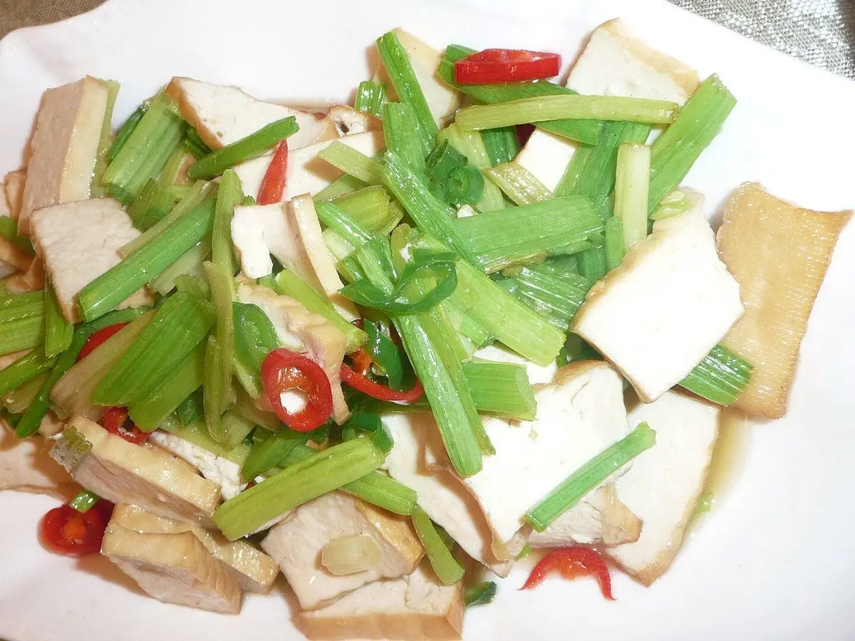 Plato con tofu cortado, tiras de apio verde y guindilla roja