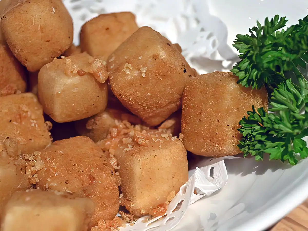 Dados de tofu frito crujientes y dorados servidos con una ramita de perejil