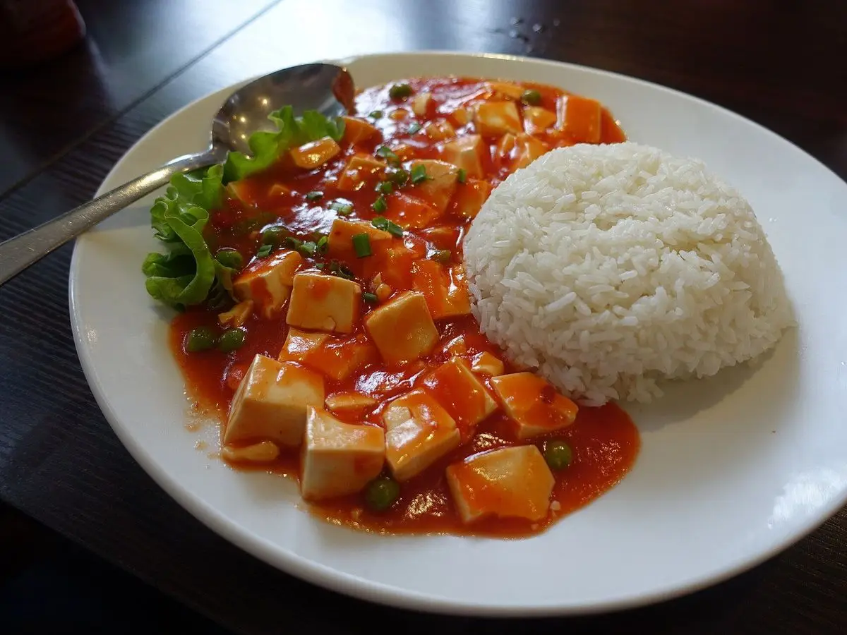 Plato con tofu en salsa roja picante estilo mapo junto a una porción de arroz blanco
