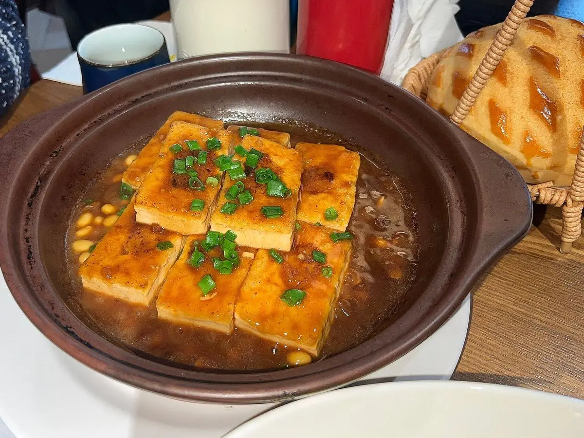 Cazuela de barro con tofu frito en dados con salsa y cebolleta picada por encima