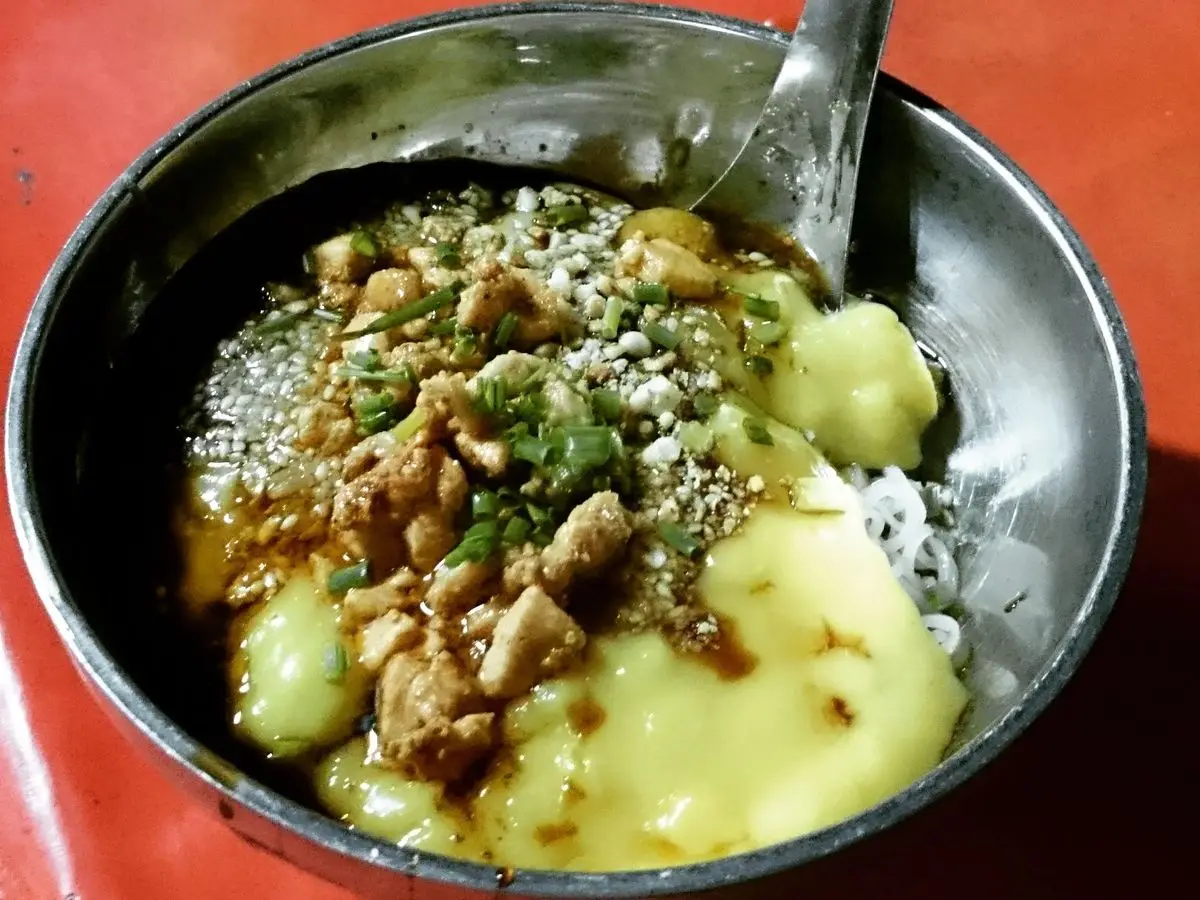 Cuenco con tofu amarillo de garbanzo, cacahuetes picados y cebolla frita por encima