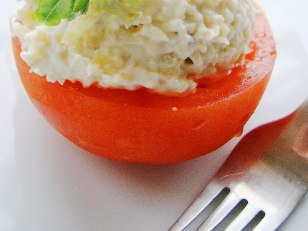 Tomate relleno de crema blanca de arroz o queso con hojas de albahaca fresca