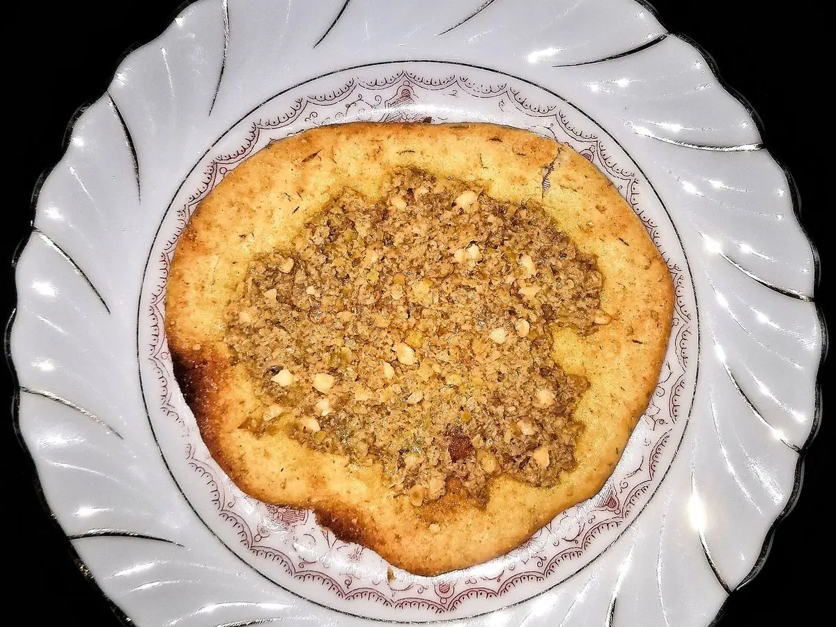 Torta de aceite dorada con semillas por encima en un plato blanco con borde decorado