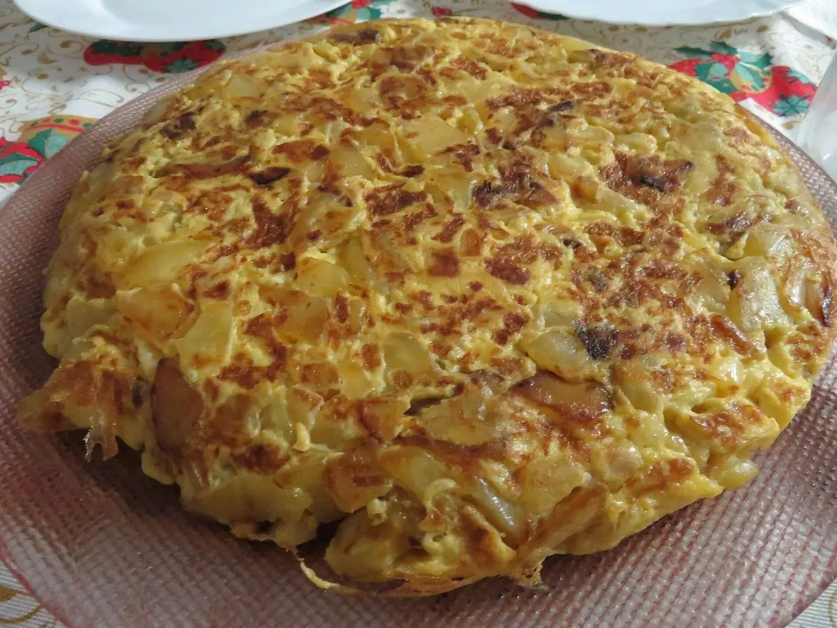 Tortilla redonda dorada con verdura sobre un plato grande