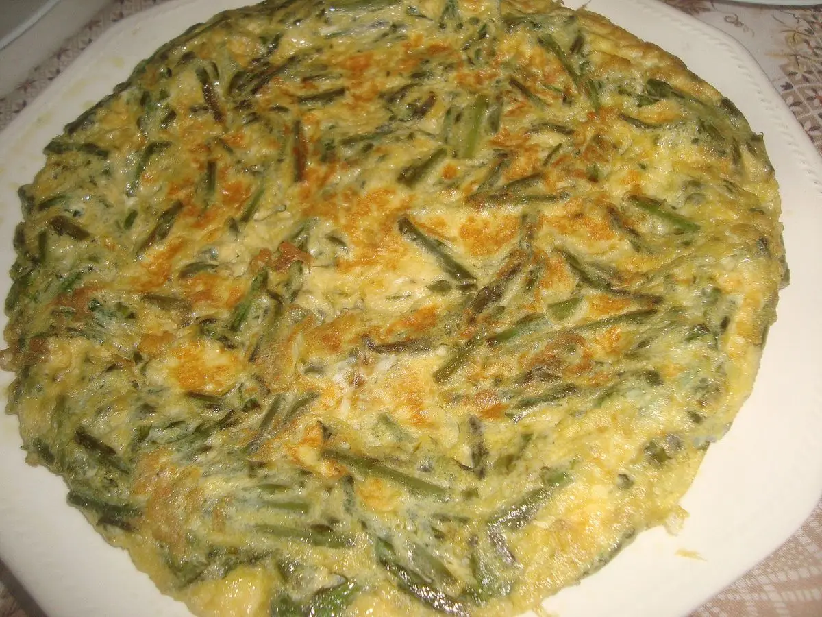 Tortilla redonda con espárragos verdes troceados sobre un plato blanco