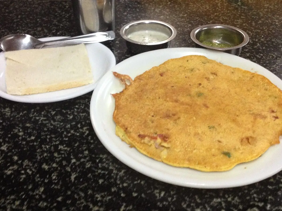Tortilla redonda dorada con trocitos de verdura en un plato blanco sobre una encimera oscura