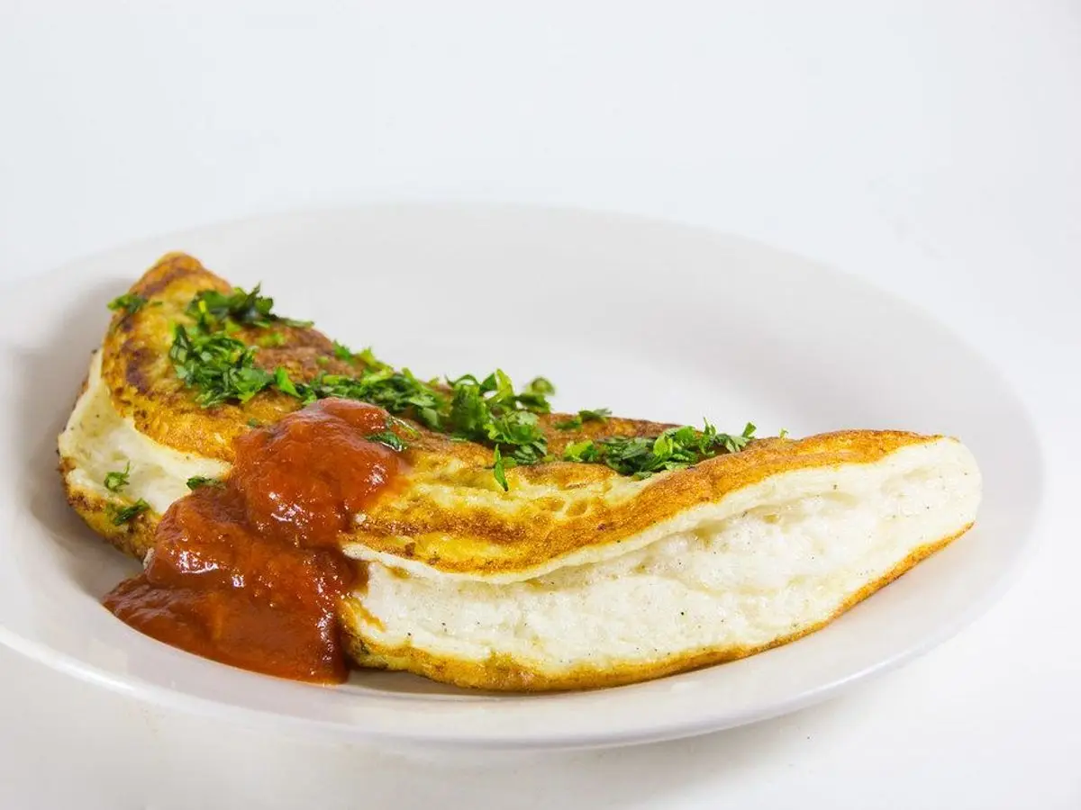 Tortilla doblada con salsa de tomate y hierbas picadas en un plato blanco
