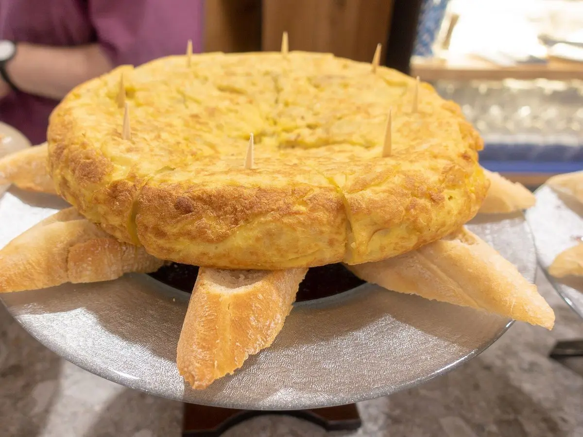 Tortilla de patatas entera servida sobre trozos de pan