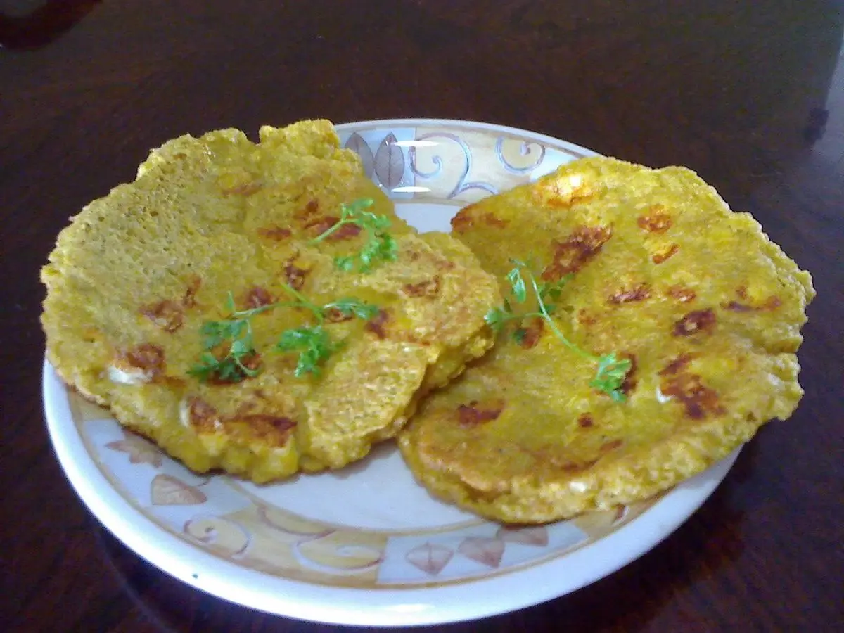 Dos tortitas doradas de plátano con hierbas servidas en un plato de cerámica