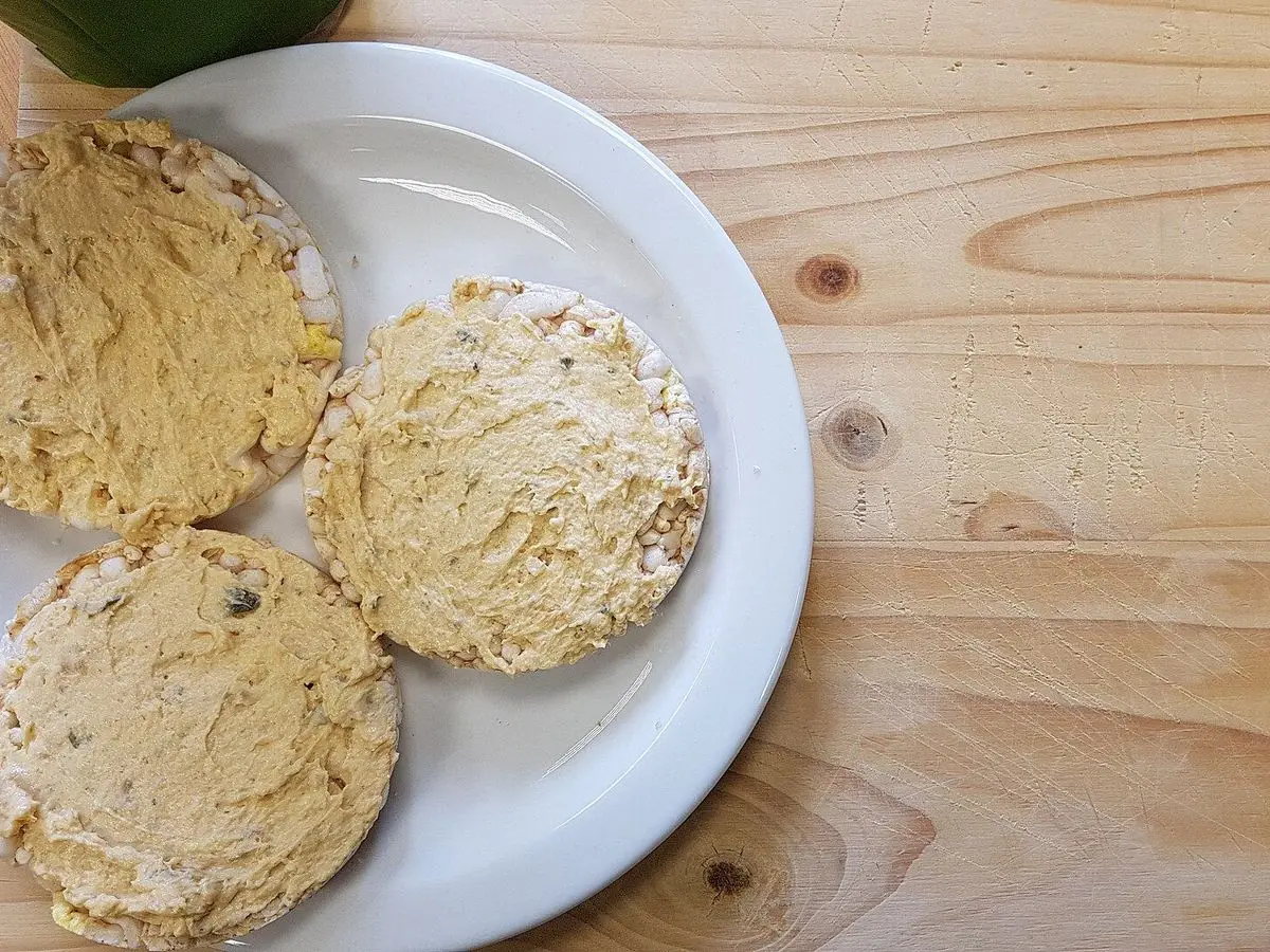 Tortitas de arroz untadas con crema sobre un plato blanco encima de una mesa de madera