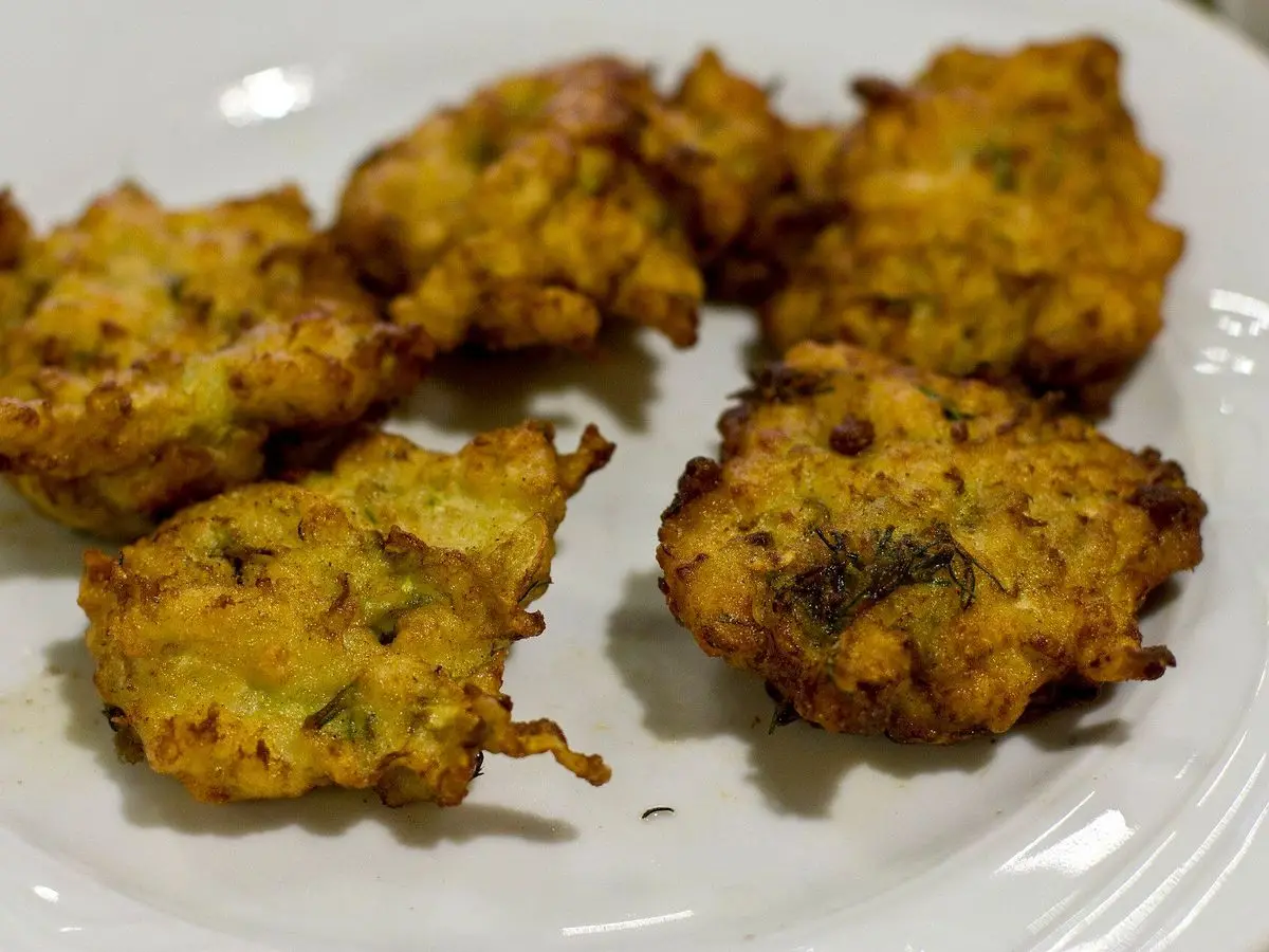 Plato blanco con tortitas de calabacín fritas, doradas e irregulares