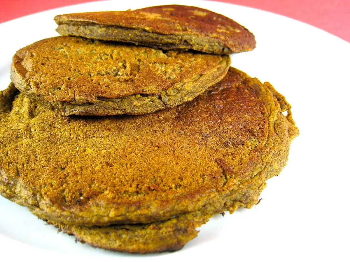 Pila de tortitas anaranjadas especiadas sobre un plato blanco