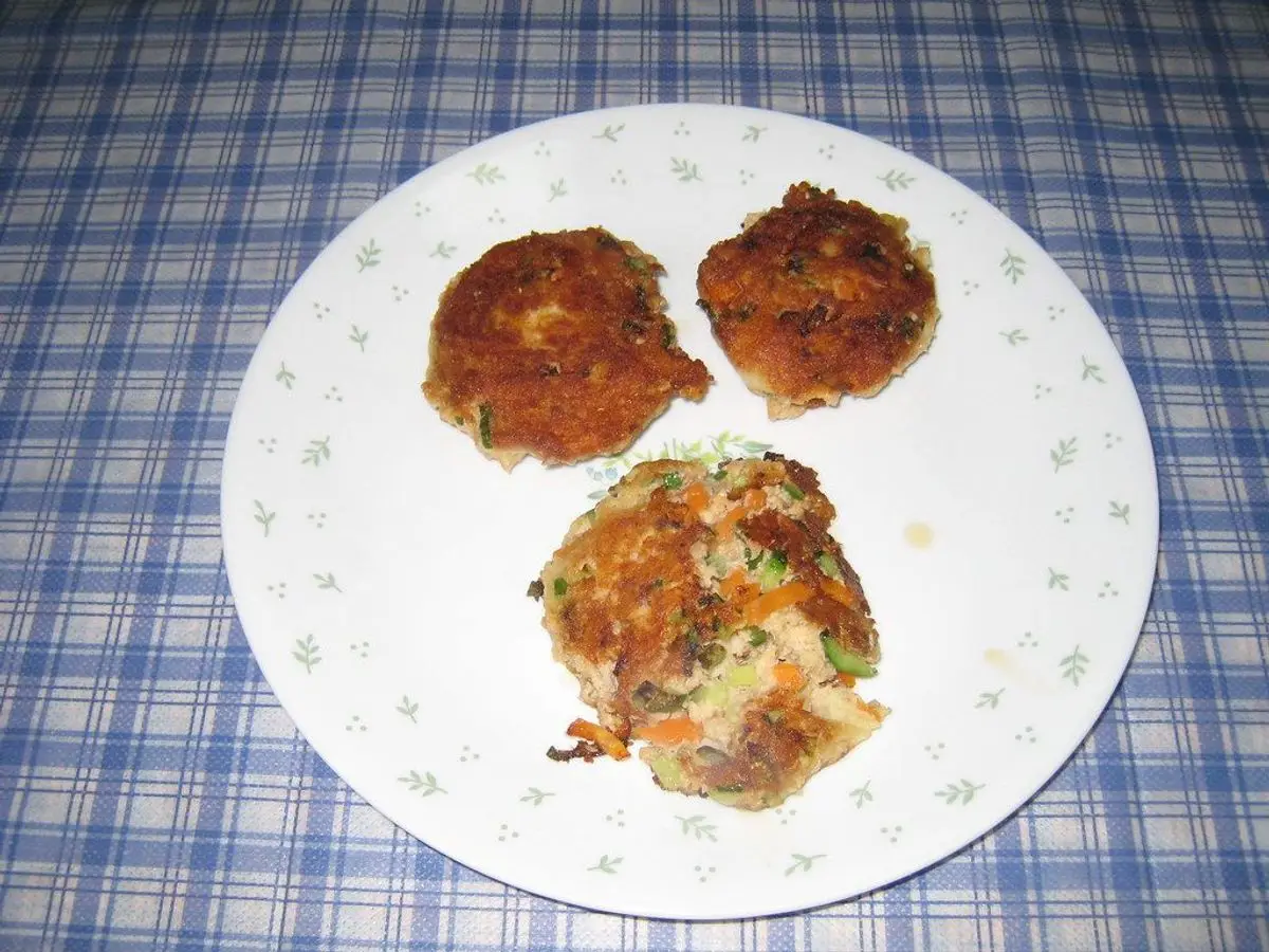 Plato con tres tortitas doradas de salmón sobre un mantel de cuadros azules