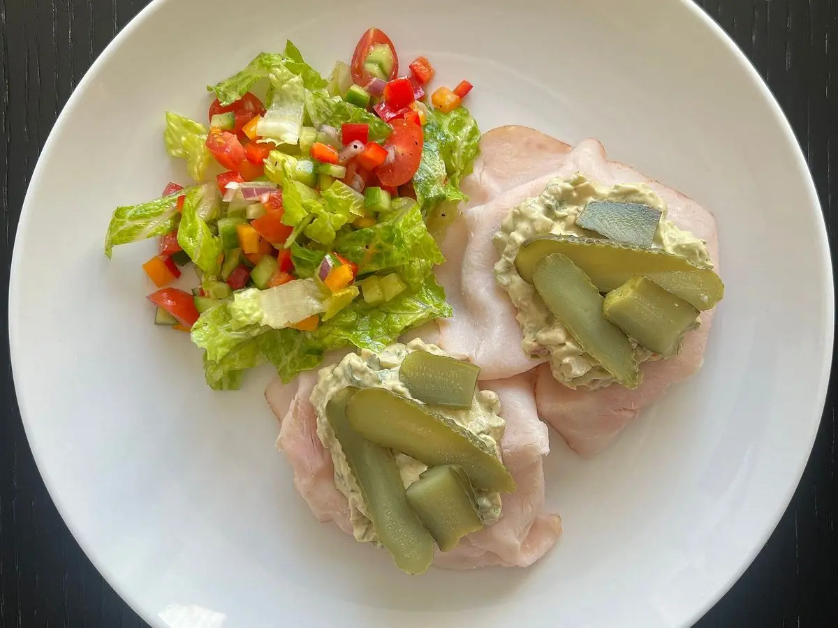 Sándwich abierto de pavo en lonchas con rodajas de pepino y ensalada de verduras en dados