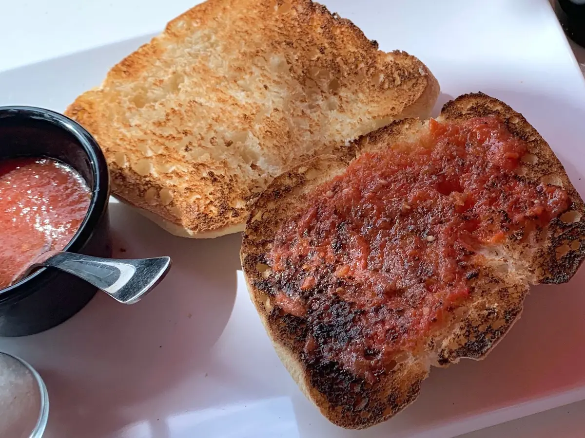 Tostadas con tomate y aceite junto a un cuenco de salsa de tomate
