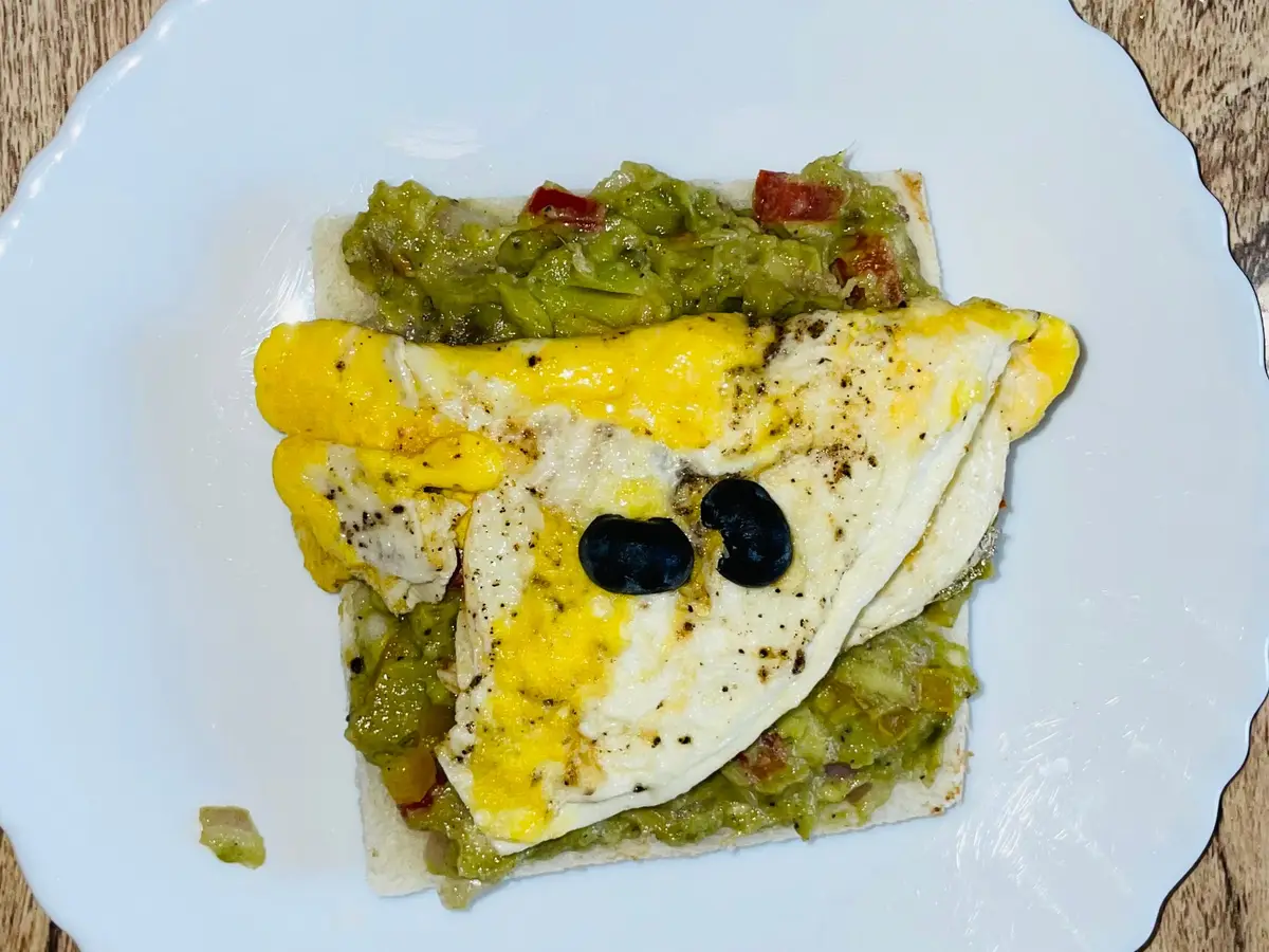 Tostada con aguacate machacado, tortilla doblada y aceitunas negras