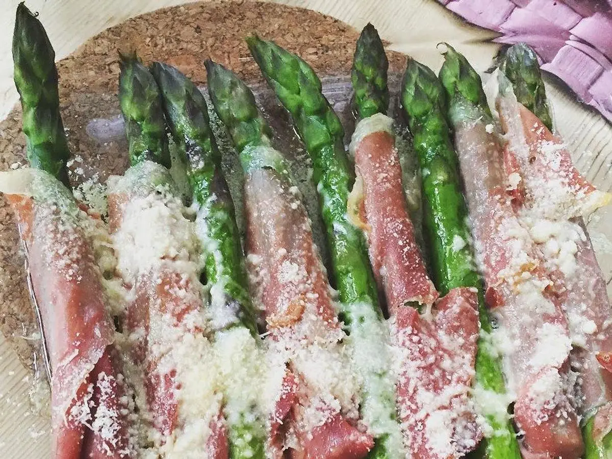 Espárragos verdes envueltos en jamón curado y cubiertos de parmesano rallado