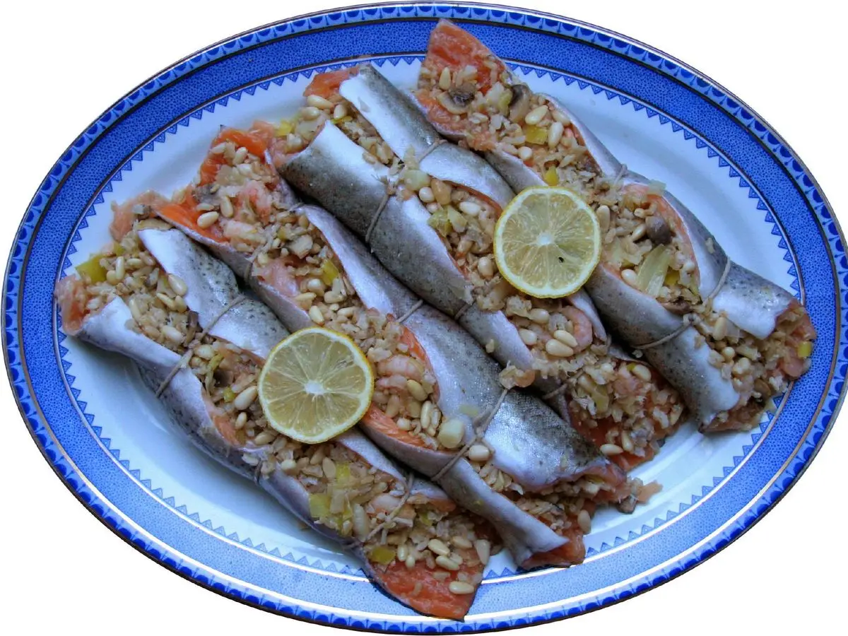 Truchas rellenas al horno con setas, arroz y verduras, decoradas con rodajas de lima en una fuente azul