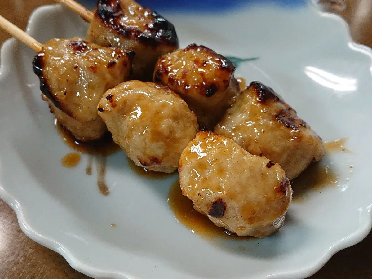 Brocheta de albóndigas de pollo glaseadas con salsa oscura en un plato azul