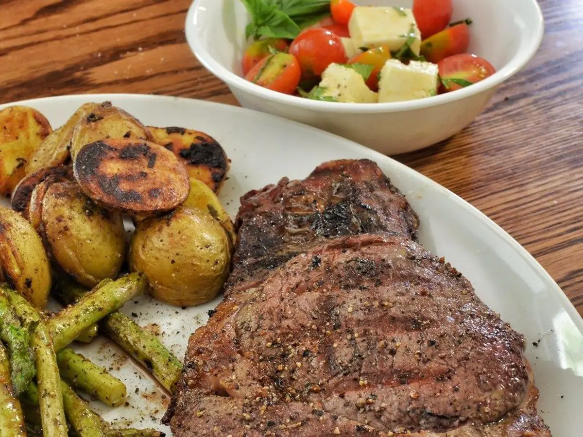 Filete de ternera a la plancha con patatas asadas y judías verdes y un cuenco de ensalada de tomate