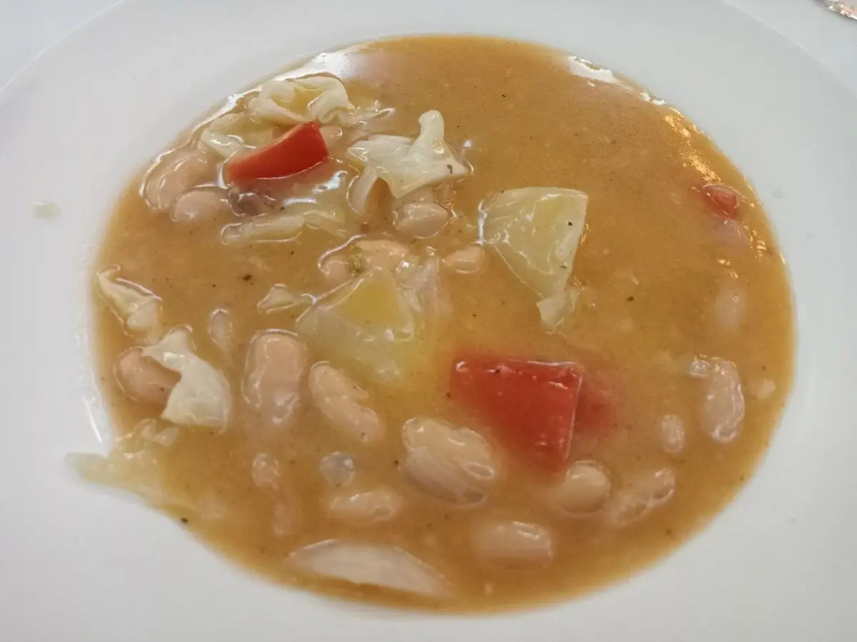 Plato hondo de guiso de alubias blancas con tomate y patata en caldo