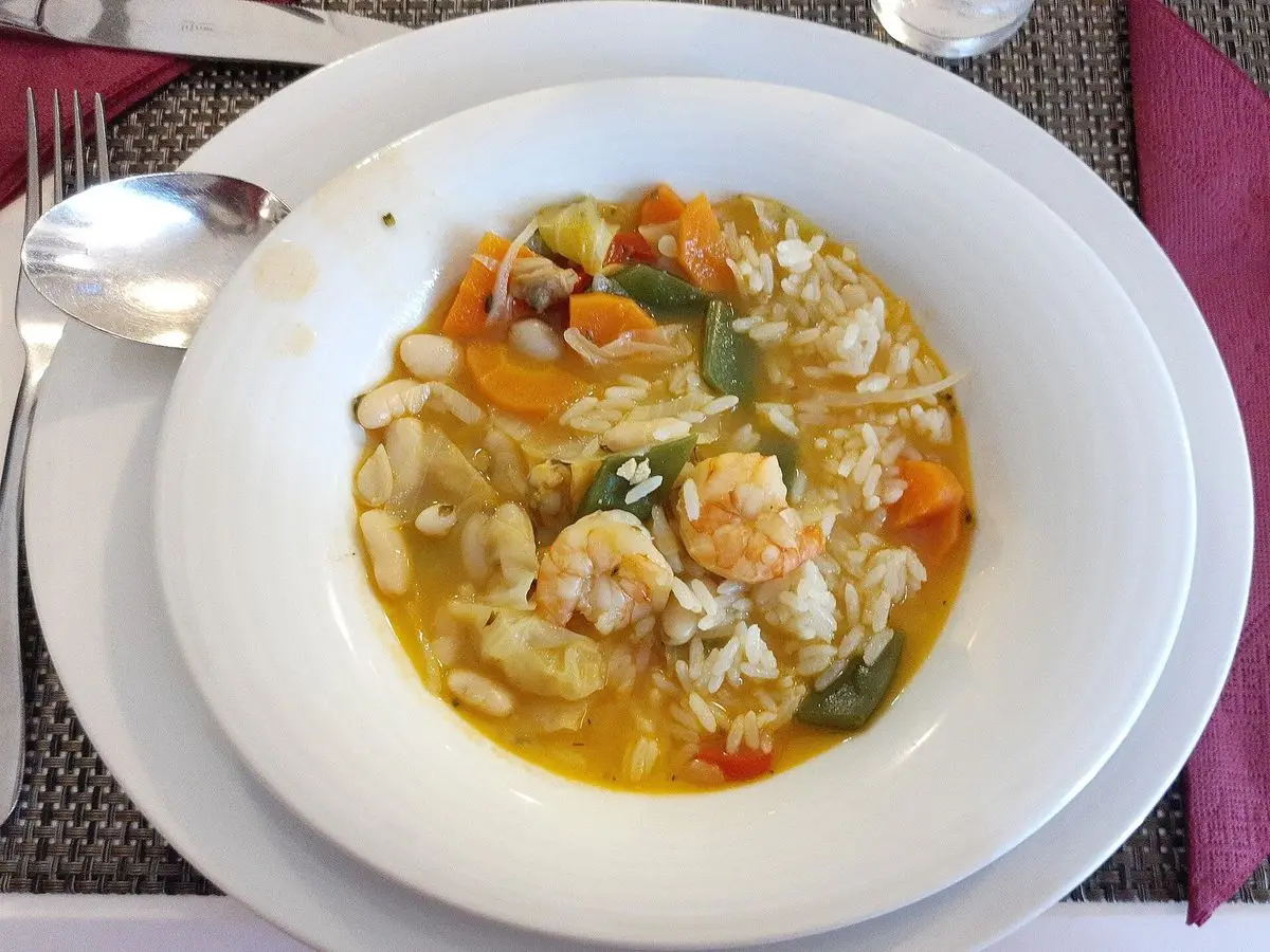 Plato hondo de guiso caldoso de alubias con gambas, zanahoria y judías verdes