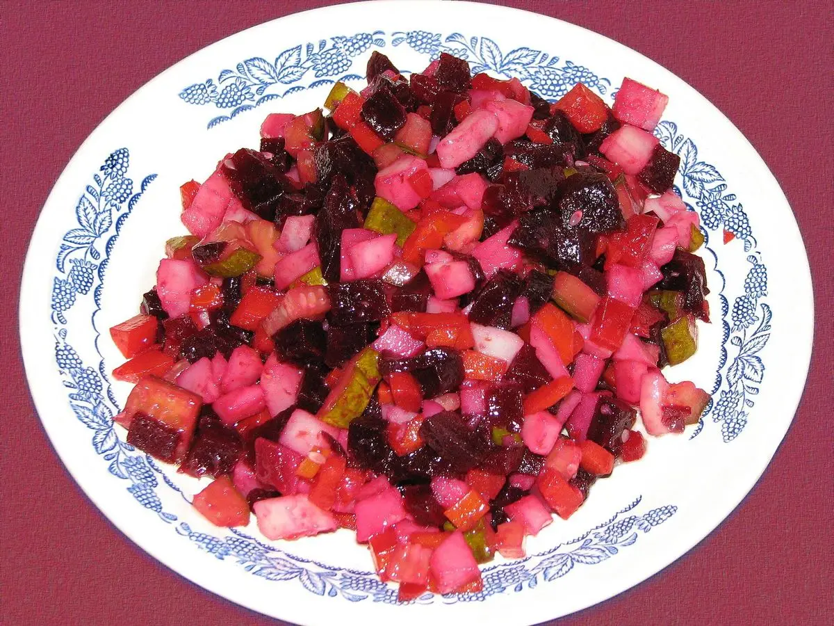 Ensalada rusa de remolacha, patata y verduras en dados en un plato blanco con dibujos azules