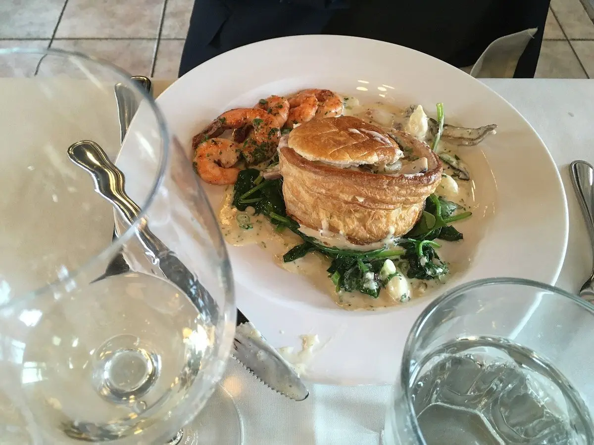 Vol-au-vent de hojaldre relleno con guarnición de verduras salteadas en un plato blanco