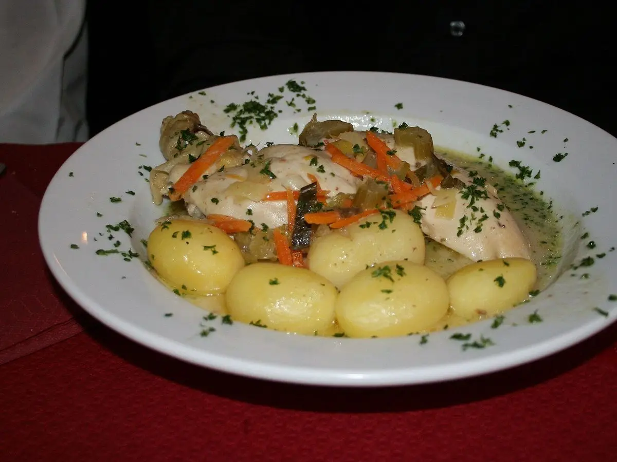 Plato de pollo en salsa cremosa con patatas cocidas, zanahoria y perejil