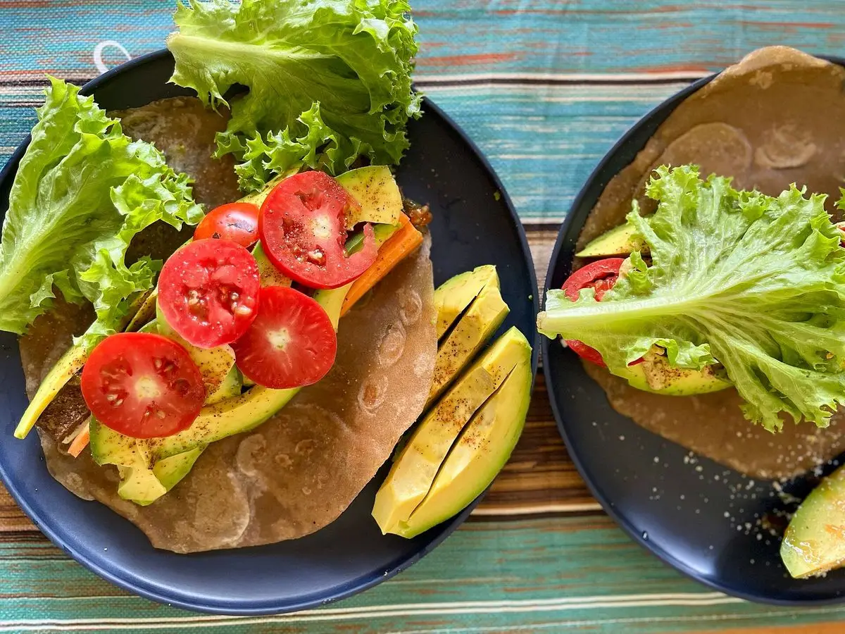 Wrap de tortilla con carne de ternera, lechuga, tomate cherry y aguacate en un plato oscuro