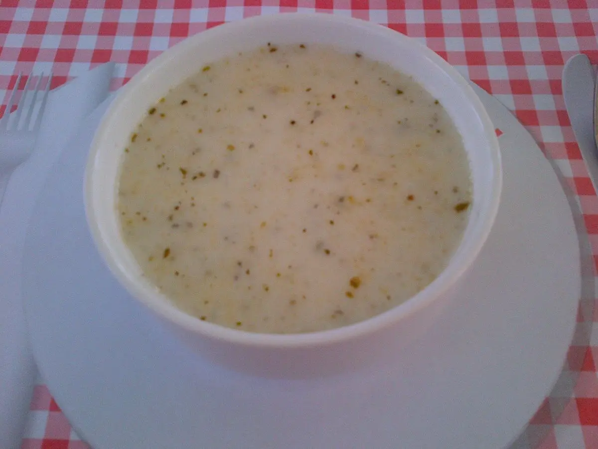 Cuenco blanco de sopa cremosa de yogur con hierbabuena seca sobre un mantel de cuadros rojos