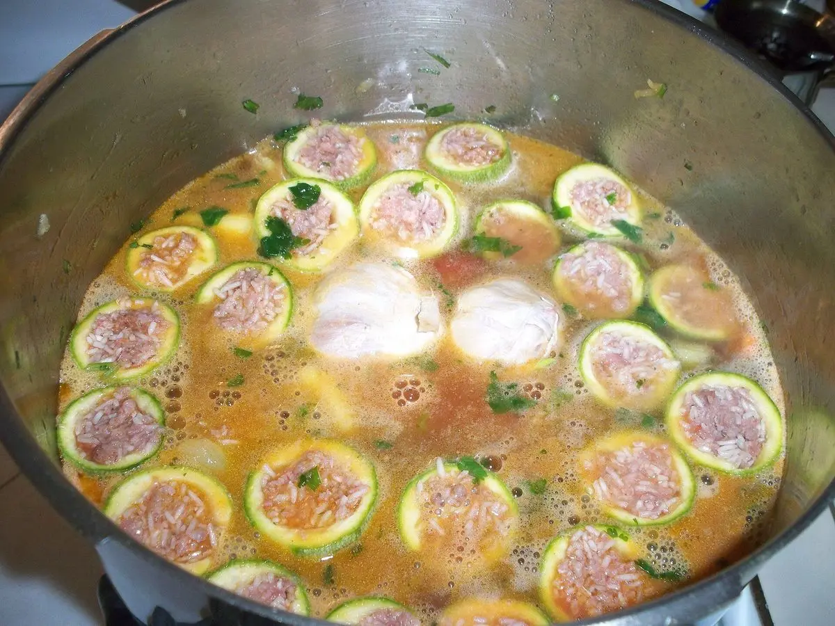Cacerola con rodajas de calabacín rellenas guisadas en salsa de tomate con relleno visible