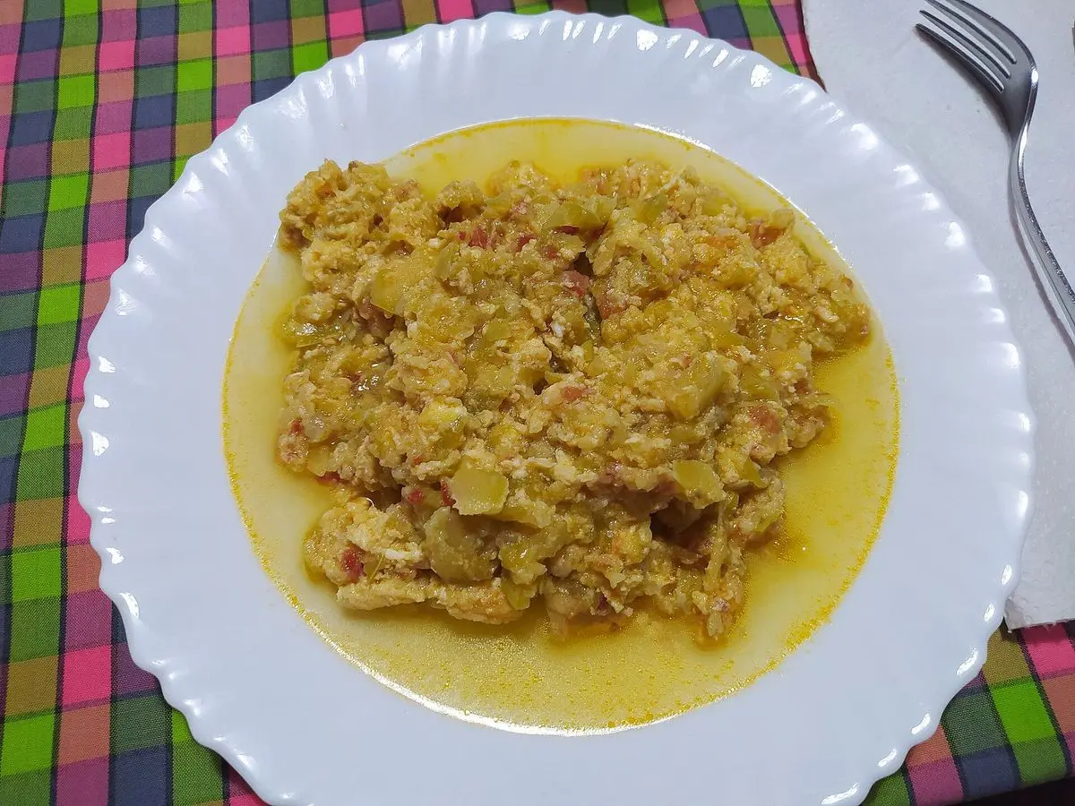 Plato blanco con revuelto de calabacín, cebolla y huevo