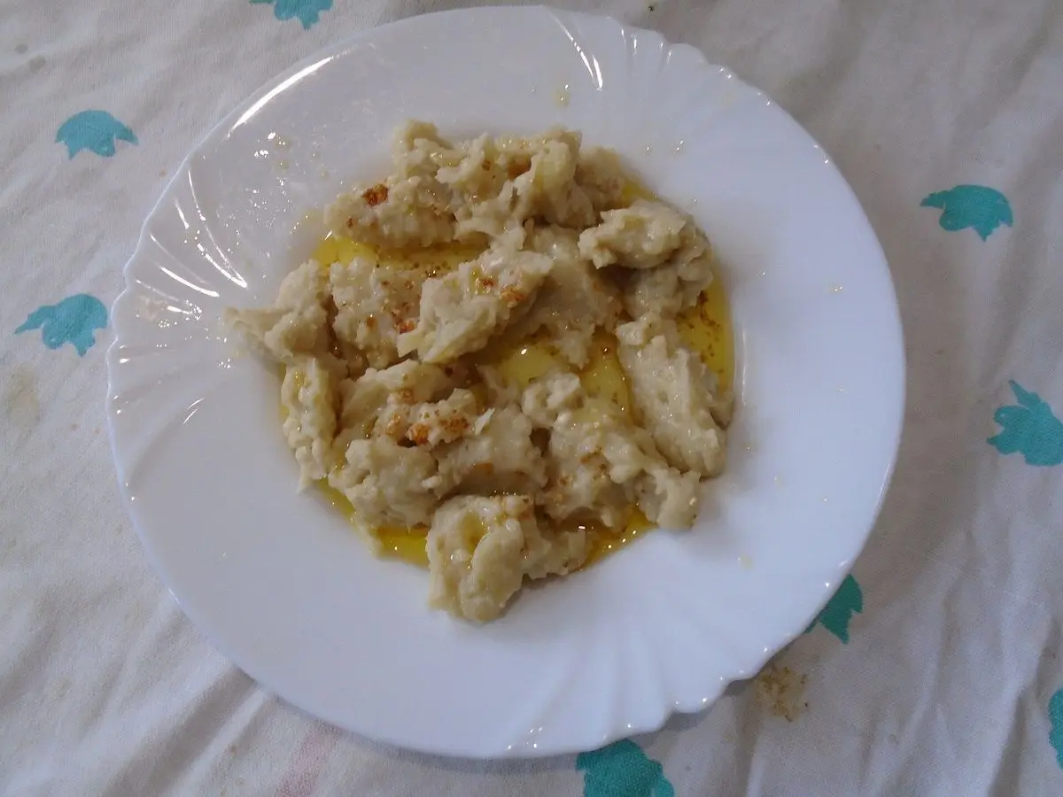 Plato blanco con žganci, bolitas de harina cocida desmenuzadas con mantequilla derretida