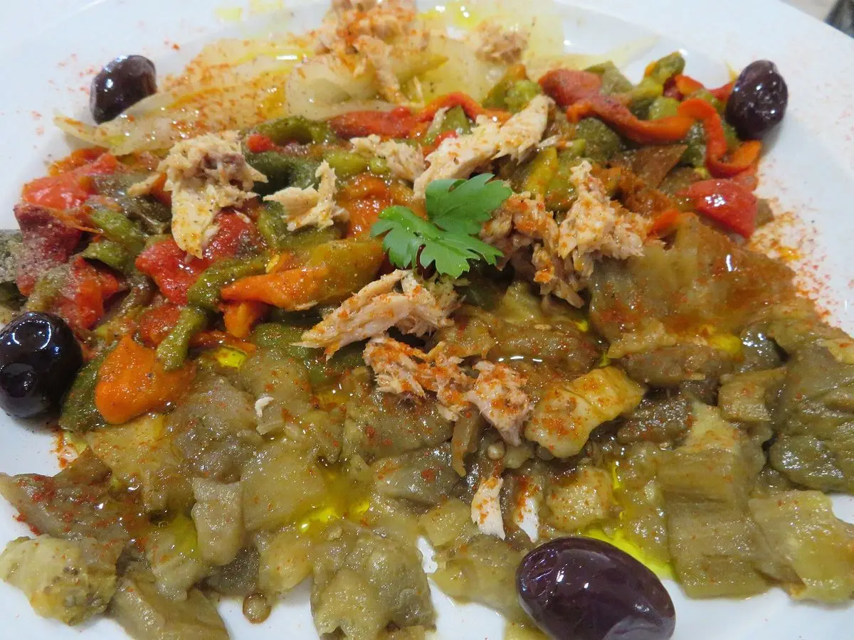 Plato de pimientos y berenjena asados en tiras con atún desmigado, aceitunas negras y perejil